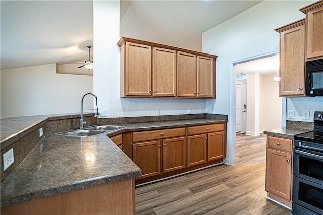 kitchen with vaulted ceiling, wood-type flooring, sink, double oven range, and kitchen peninsula