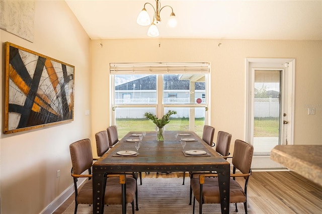 dining room with hardwood / wood-style flooring, plenty of natural light, and an inviting chandelier