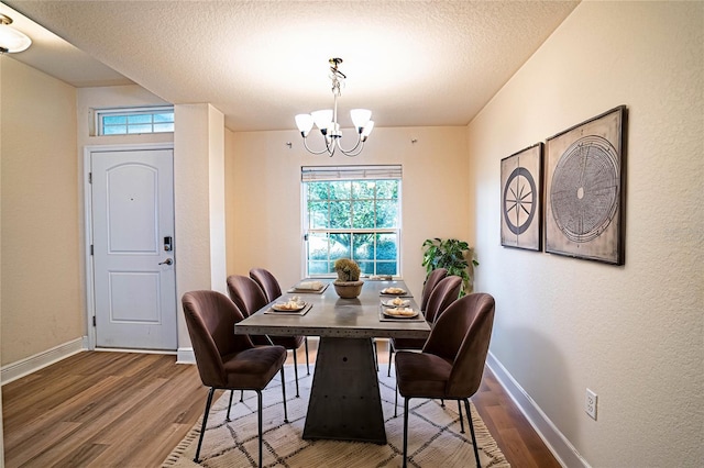 dining area with a chandelier, hardwood / wood-style floors, a textured ceiling, and a wealth of natural light