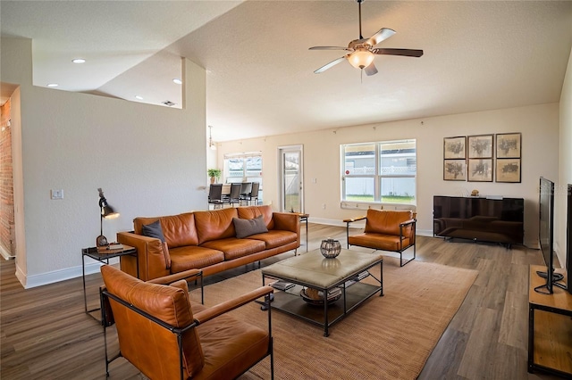 living room with lofted ceiling, hardwood / wood-style flooring, a textured ceiling, and ceiling fan