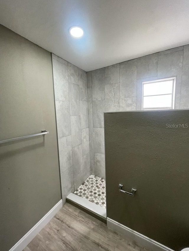 bathroom featuring wood-type flooring and tiled shower