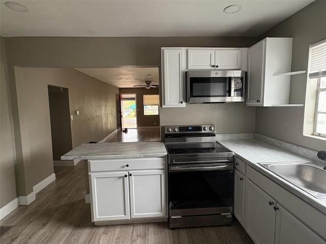 kitchen with white cabinets, stainless steel appliances, kitchen peninsula, and sink