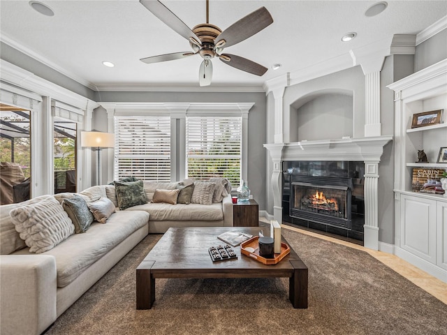 living room with a tiled fireplace, crown molding, and a healthy amount of sunlight