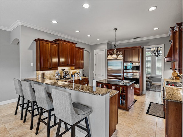 kitchen featuring a center island, hanging light fixtures, dark stone countertops, kitchen peninsula, and decorative backsplash