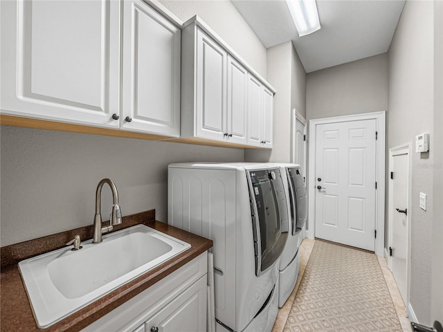 laundry room with sink, washing machine and dryer, and cabinets