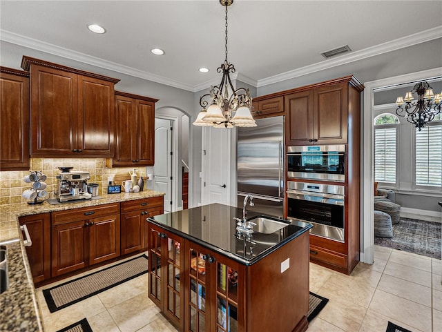 kitchen with arched walkways, light tile patterned floors, stainless steel appliances, a sink, and tasteful backsplash