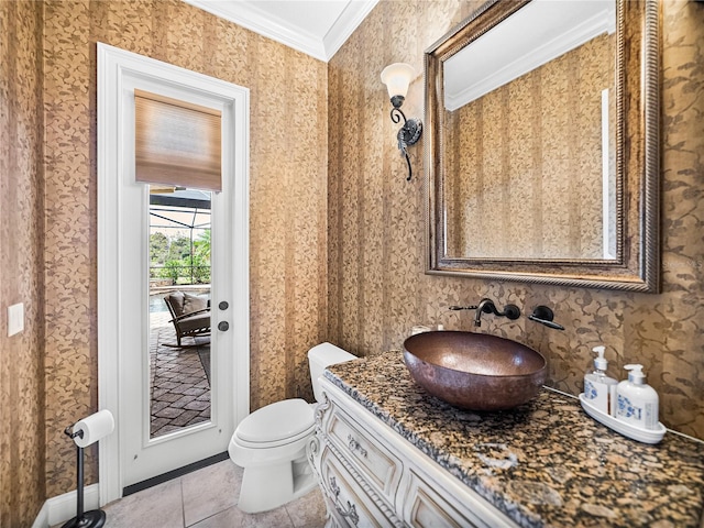 half bathroom with toilet, vanity, ornamental molding, tile patterned floors, and wallpapered walls