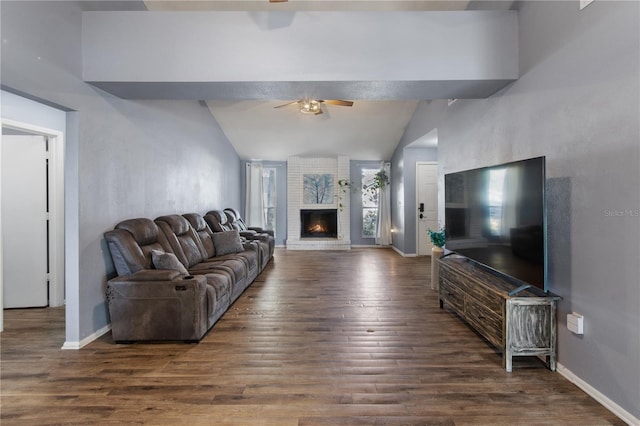 living room featuring a fireplace, vaulted ceiling, ceiling fan, and dark wood-type flooring