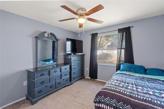 bedroom featuring light carpet, a textured ceiling, and ceiling fan