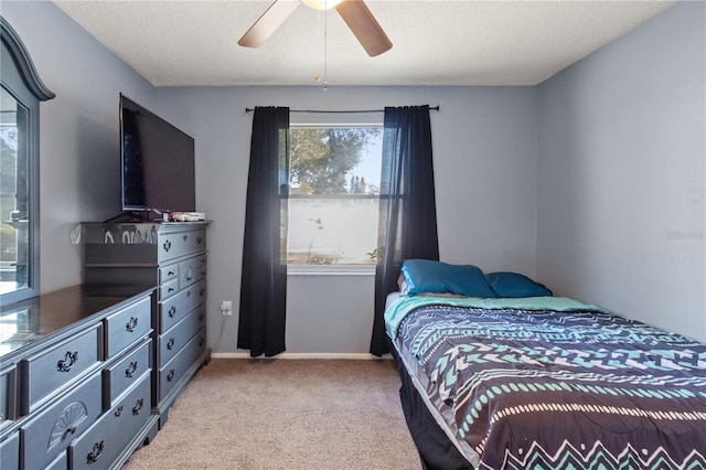 bedroom with a textured ceiling, ceiling fan, and light carpet