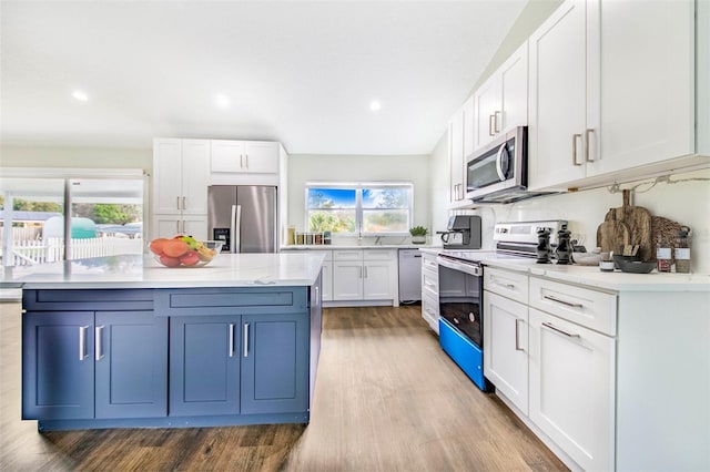 kitchen featuring decorative backsplash, stainless steel appliances, white cabinets, a center island, and light hardwood / wood-style floors