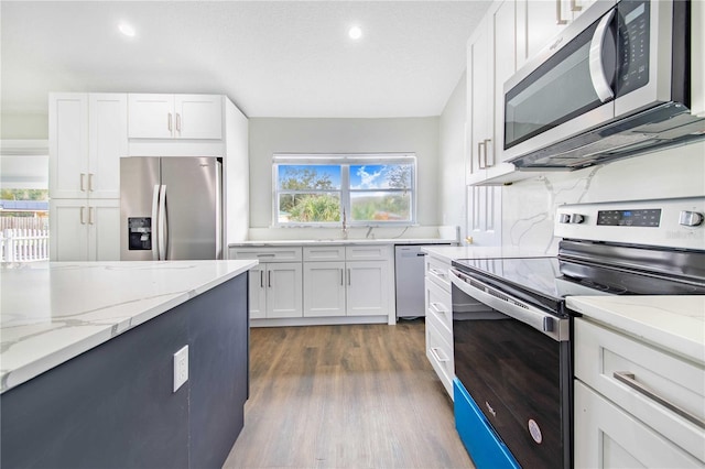 kitchen featuring light stone counters, white cabinetry, stainless steel appliances, and dark wood-type flooring