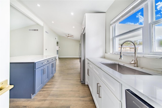 kitchen featuring white cabinets, ceiling fan, lofted ceiling, and sink