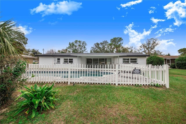 rear view of house with a yard and a fenced in pool