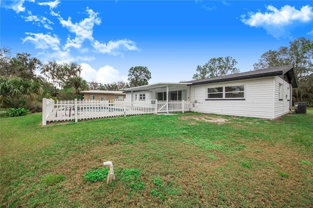 back of property with central AC unit and a lawn