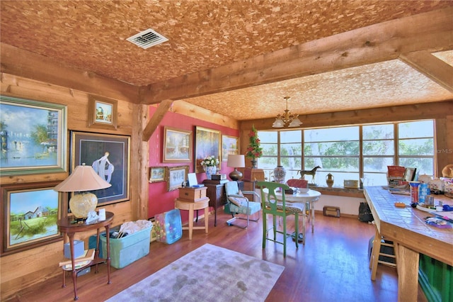 dining room featuring beam ceiling, hardwood / wood-style floors, a healthy amount of sunlight, and an inviting chandelier