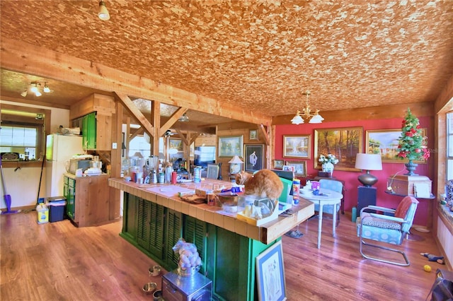 kitchen with light wood-type flooring, an inviting chandelier, tile counters, and green cabinetry