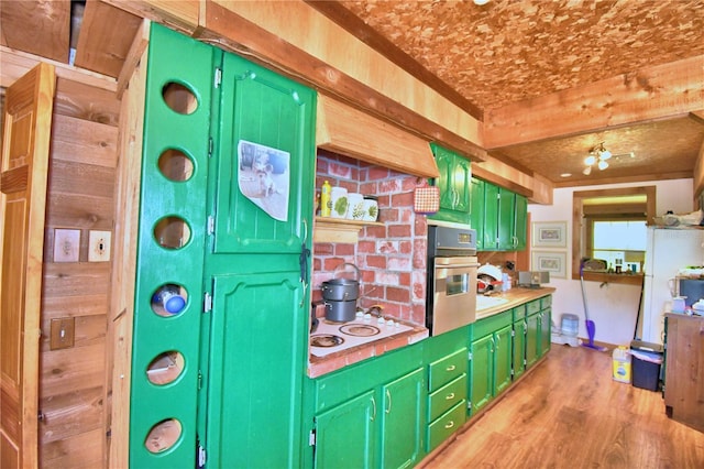 kitchen featuring wall oven, white electric cooktop, light hardwood / wood-style flooring, and green cabinets