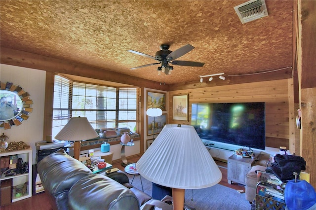 living room featuring ceiling fan, track lighting, wood walls, and hardwood / wood-style flooring