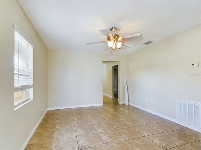 spare room featuring plenty of natural light, light tile patterned flooring, a textured ceiling, and ceiling fan