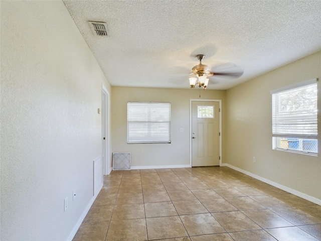 foyer entrance with ceiling fan, light tile patterned flooring, and a textured ceiling