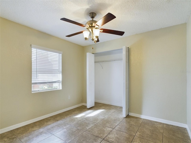 unfurnished bedroom featuring ceiling fan, light tile patterned floors, a textured ceiling, and a closet