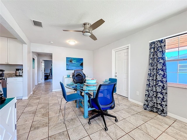 dining room featuring ceiling fan, light tile patterned flooring, and a textured ceiling