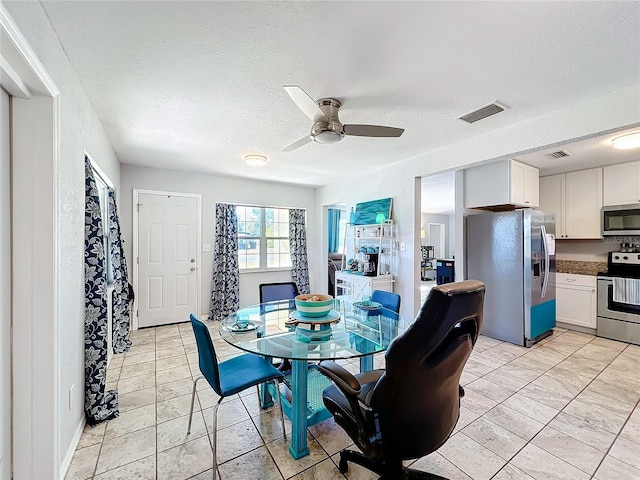 dining space featuring ceiling fan and a textured ceiling