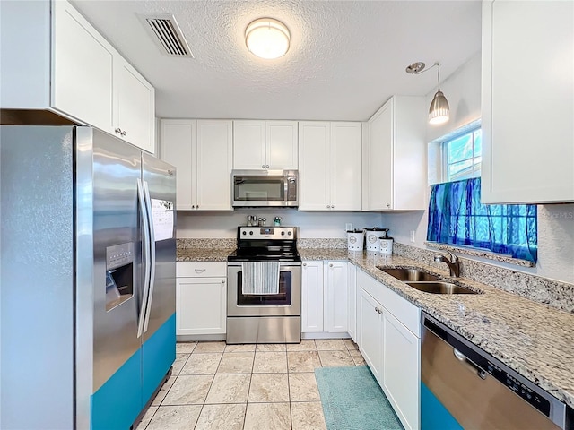 kitchen featuring a textured ceiling, stainless steel appliances, sink, pendant lighting, and white cabinets