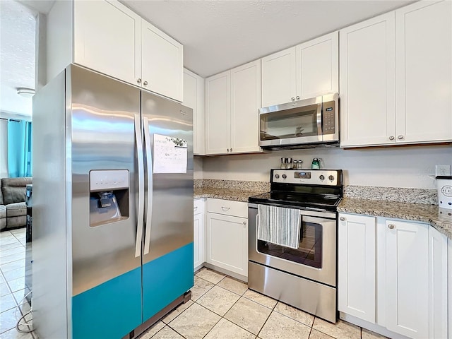 kitchen with light tile patterned flooring, light stone countertops, white cabinetry, and appliances with stainless steel finishes