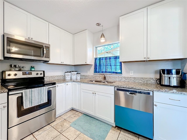 kitchen featuring stainless steel appliances, sink, light tile patterned floors, decorative light fixtures, and white cabinets