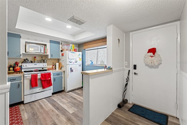 kitchen featuring backsplash, white appliances, a tray ceiling, a textured ceiling, and light hardwood / wood-style flooring