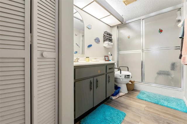 bathroom with walk in shower, toilet, a textured ceiling, vanity, and hardwood / wood-style flooring