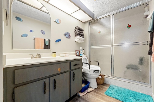 bathroom featuring toilet, a shower with shower door, wood-type flooring, a textured ceiling, and vanity