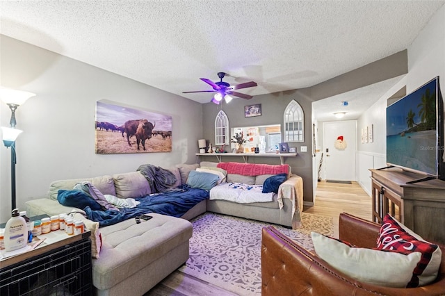 living room with hardwood / wood-style flooring, ceiling fan, and a textured ceiling