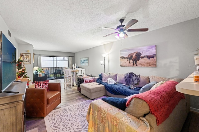 living room with ceiling fan, a textured ceiling, and light hardwood / wood-style floors