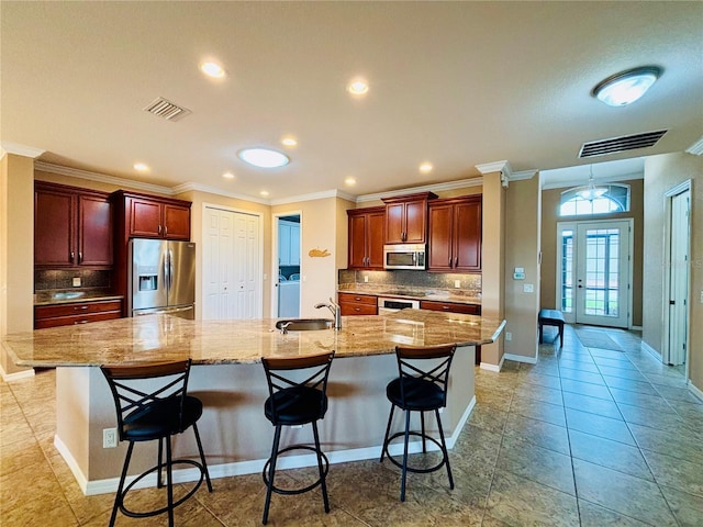 kitchen with backsplash, sink, appliances with stainless steel finishes, a large island, and a kitchen bar