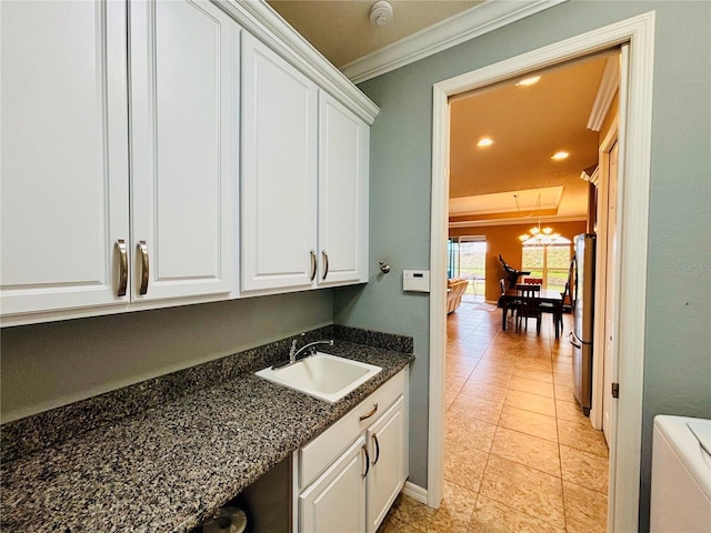 interior space featuring cabinets, ornamental molding, sink, light tile patterned floors, and washer / dryer