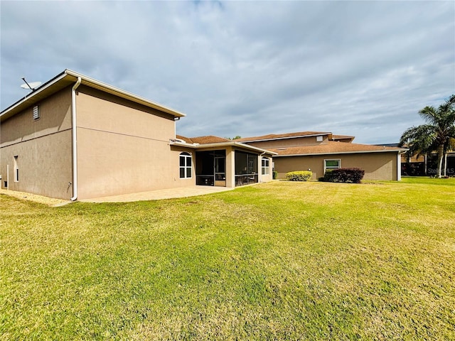 rear view of property featuring a sunroom, a patio area, and a yard