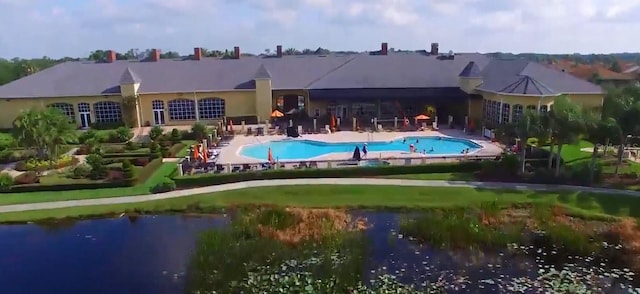 back of property with a patio, a water view, and a community pool