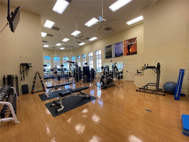 exercise room featuring hardwood / wood-style floors, ceiling fan, and a high ceiling