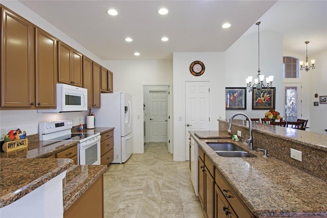 kitchen with brown cabinets, recessed lighting, an inviting chandelier, a sink, and white appliances