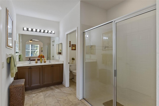 full bathroom with double vanity, a stall shower, a sink, and toilet