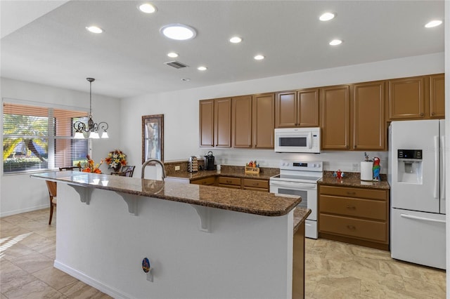 kitchen featuring white appliances, visible vents, dark stone counters, hanging light fixtures, and a kitchen bar