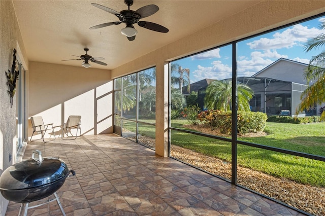 unfurnished sunroom featuring ceiling fan