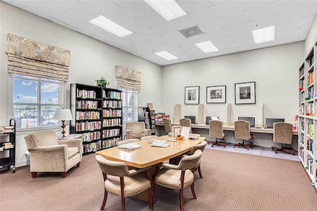 carpeted office with a paneled ceiling, plenty of natural light, and built in desk