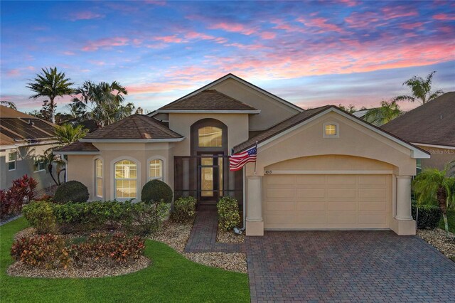 view of front of property with a garage, a shingled roof, decorative driveway, and stucco siding