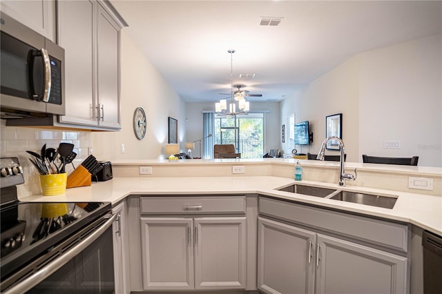 kitchen with stainless steel appliances, sink, kitchen peninsula, and gray cabinets