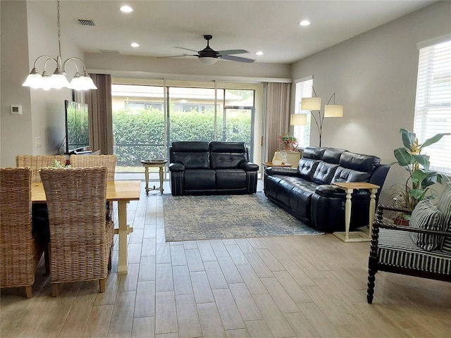 living room featuring ceiling fan with notable chandelier