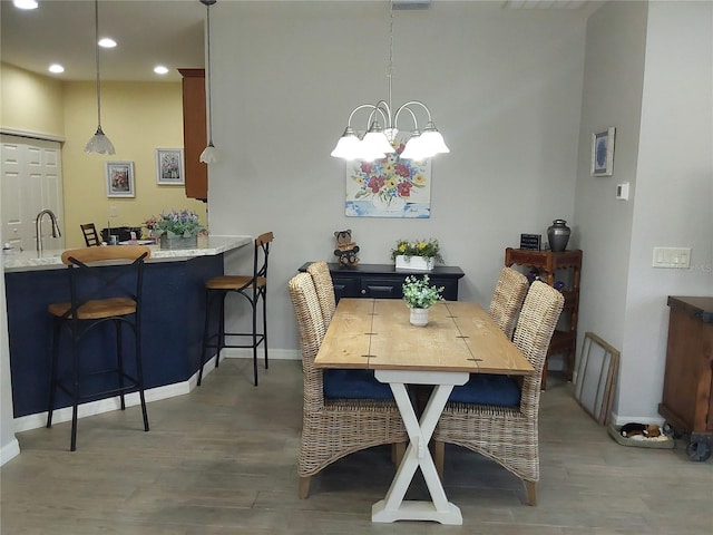 dining room with hardwood / wood-style flooring, sink, and an inviting chandelier